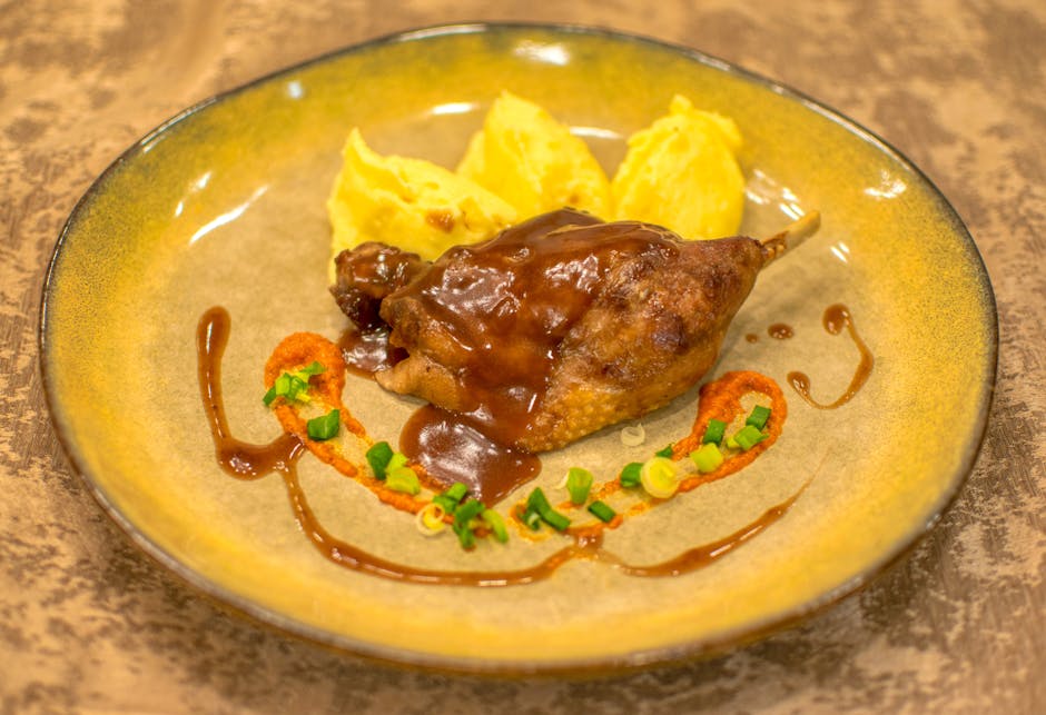 Cuisse de canard confite dorée à perfection, servie avec une purée maison et des pommes de terre sarladaises, dans une assiette rustique.
